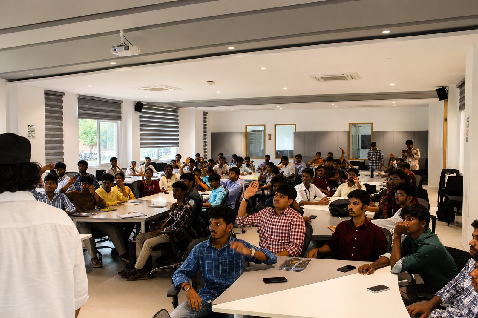 A full room of learners at an R Commerce session, many with their hands raised